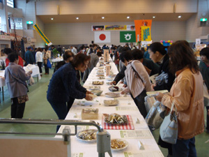郷土色豊かな料理の数々と興味津々の参加者の写真